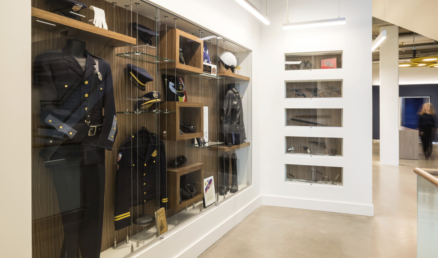 Display case behind glass in white wall. Police uniform and awards. Display case behind glass in white wall. Police uniform and awards.