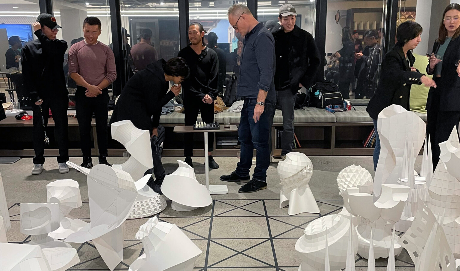 people at an event, viewing sculptures on floor in a grid, abstract geometries, folded paper, origami, life size chess, modern art