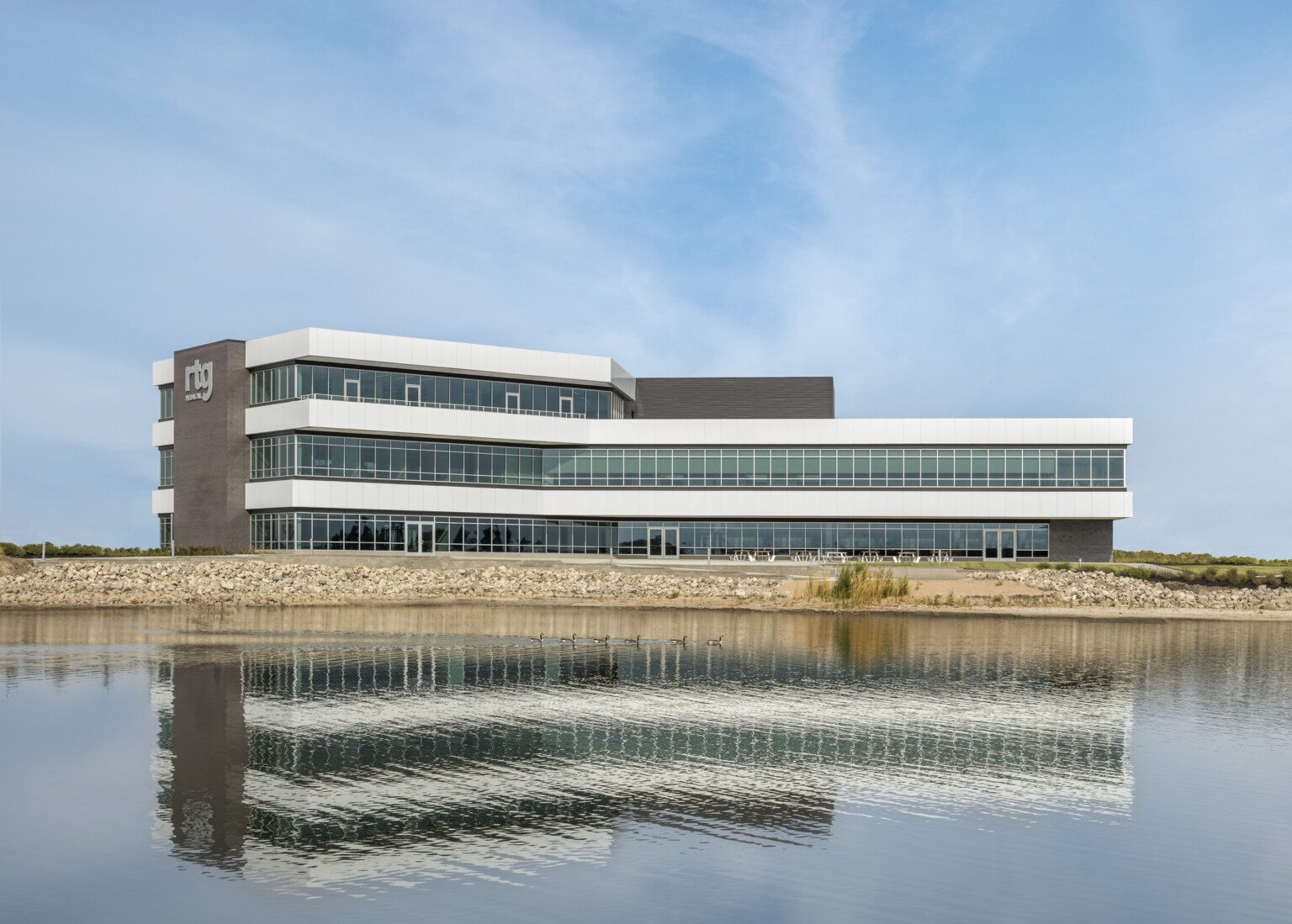 RTG Medical Headquarters, a 3 story building with floor to ceiling windows and brown wrap facade accent. Silver RTG sign