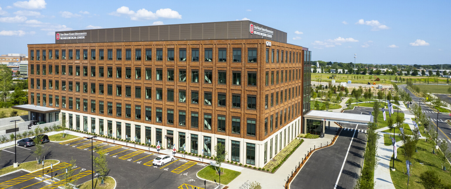 Back of brick building with white first story and large windows. Sign reads The Ohio State University Wexner Medical Center