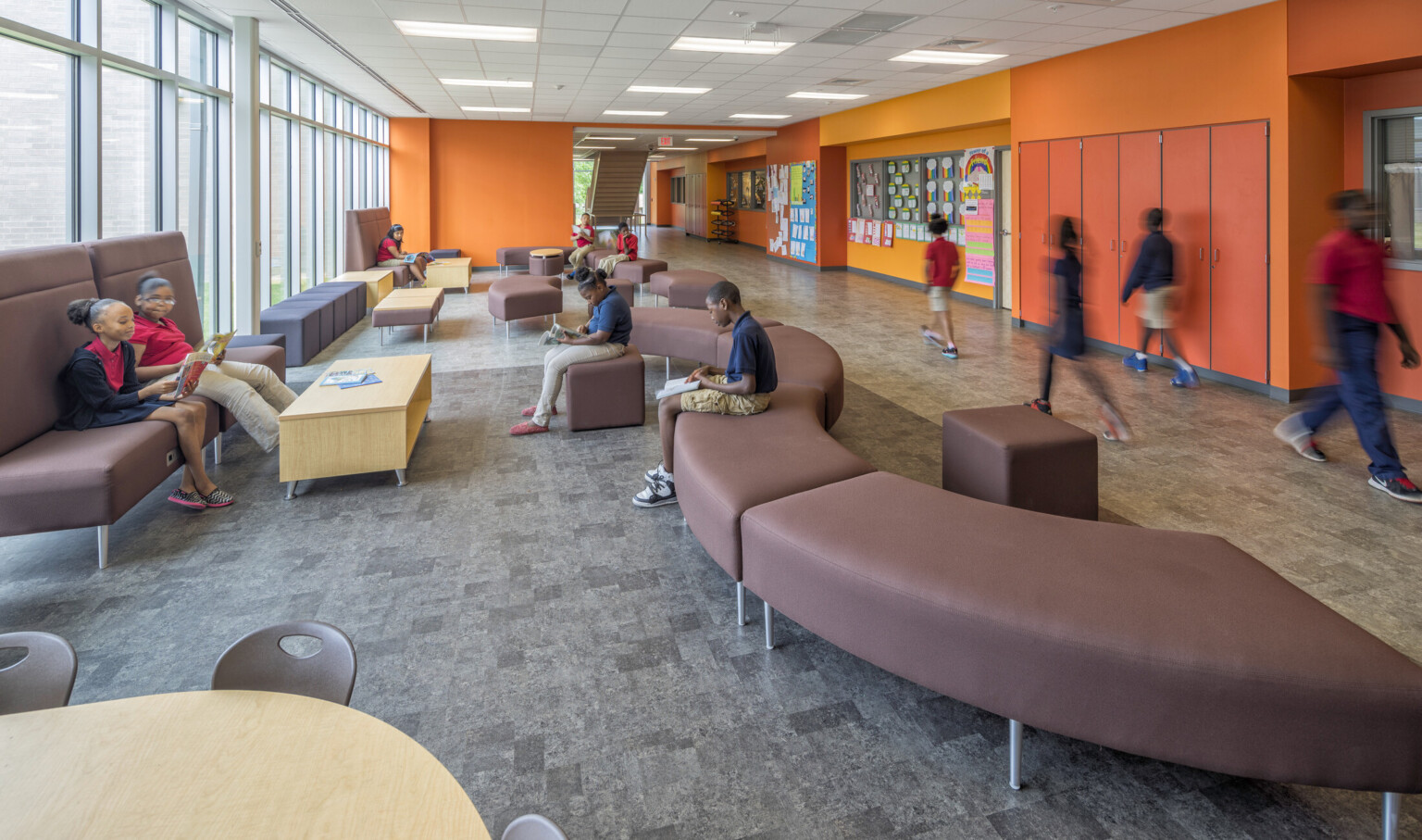 orange hallway in Boone Park Elementary School with mixed comfortable seating and floor to ceiling windows