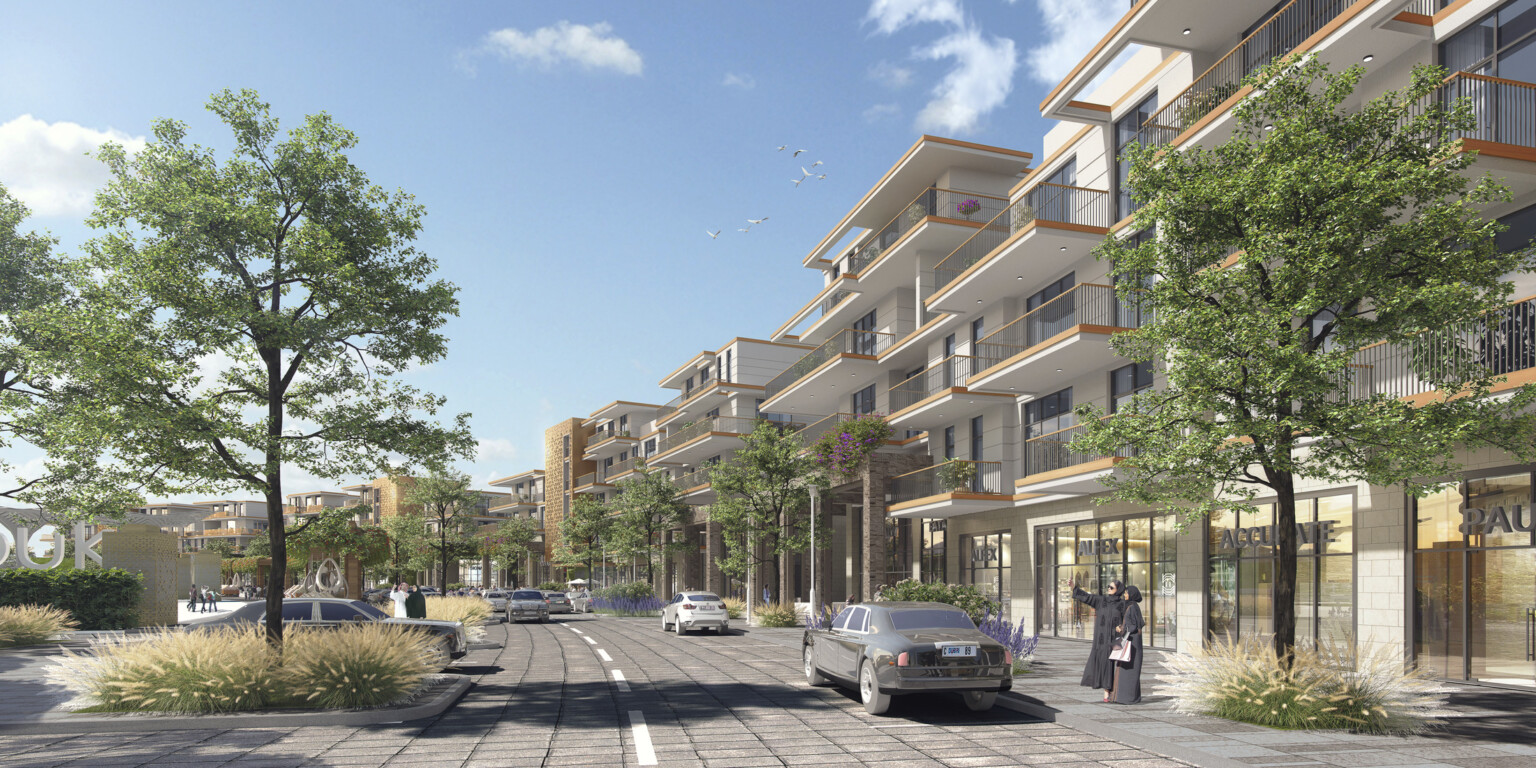 Four story apartment building lines curved street with cars and trees. Lightly colored wood accents on balconies