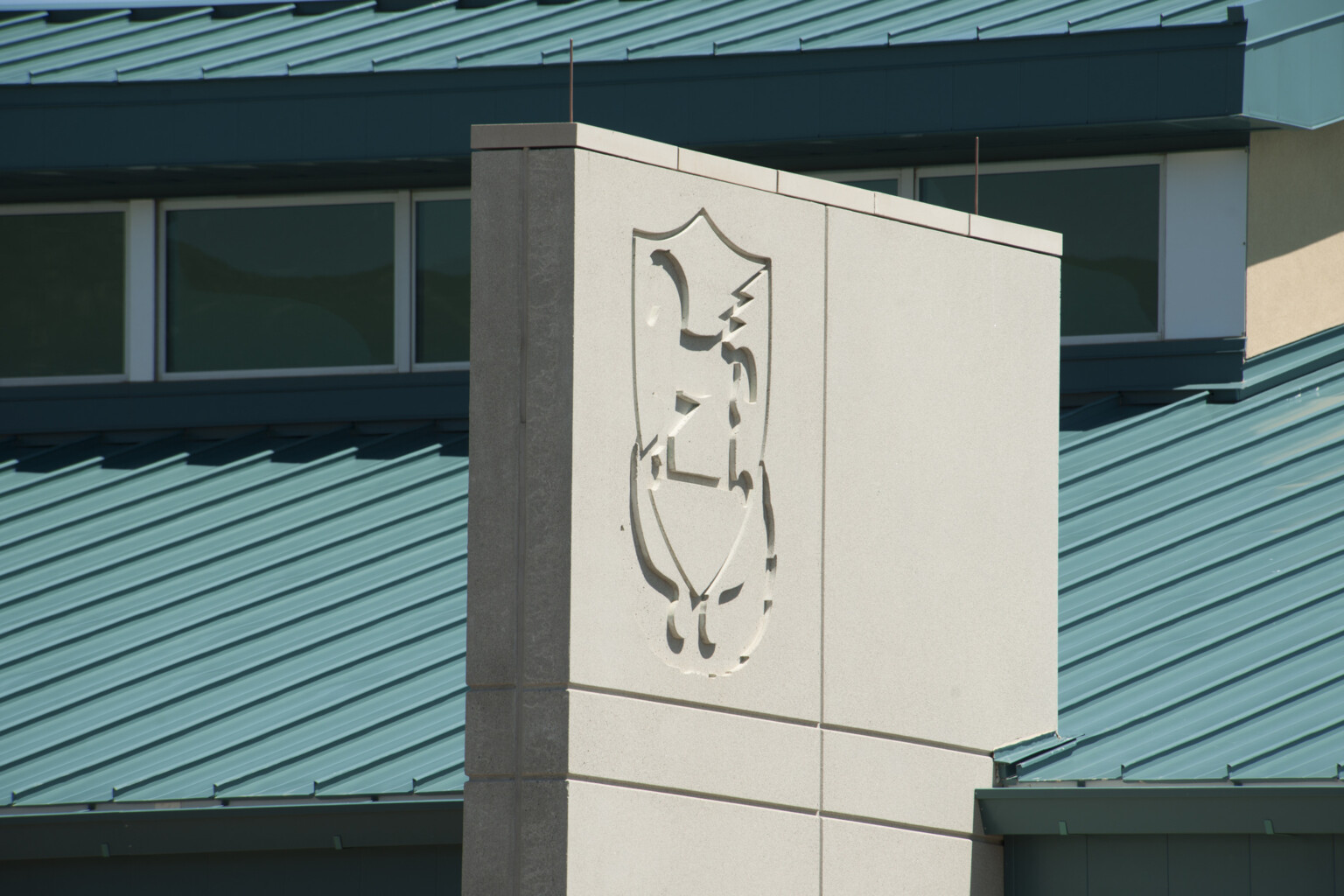 Fort Carson 10th Group SOF Battalion Operations Complex roof and grey cement accent facade panel with logo Fort Carson 10th Group SOF Battalion Operations Complex roof and grey cement accent facade panel with logo