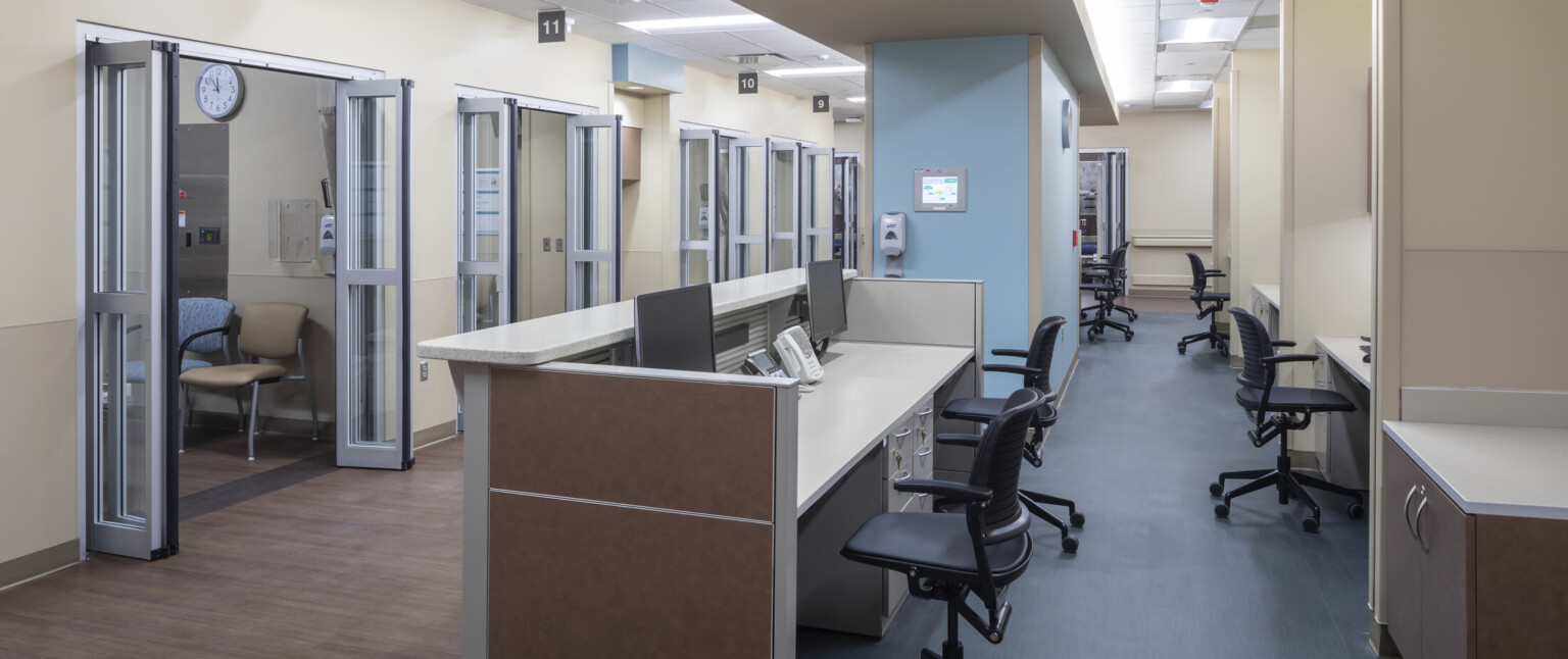 Nursing stations spread throughout hallway of hospital with light blue accent wall column