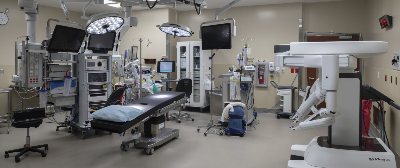 Operating room with equipment hanging over bed and along beige walls Operating room with equipment hanging over bed and along beige walls