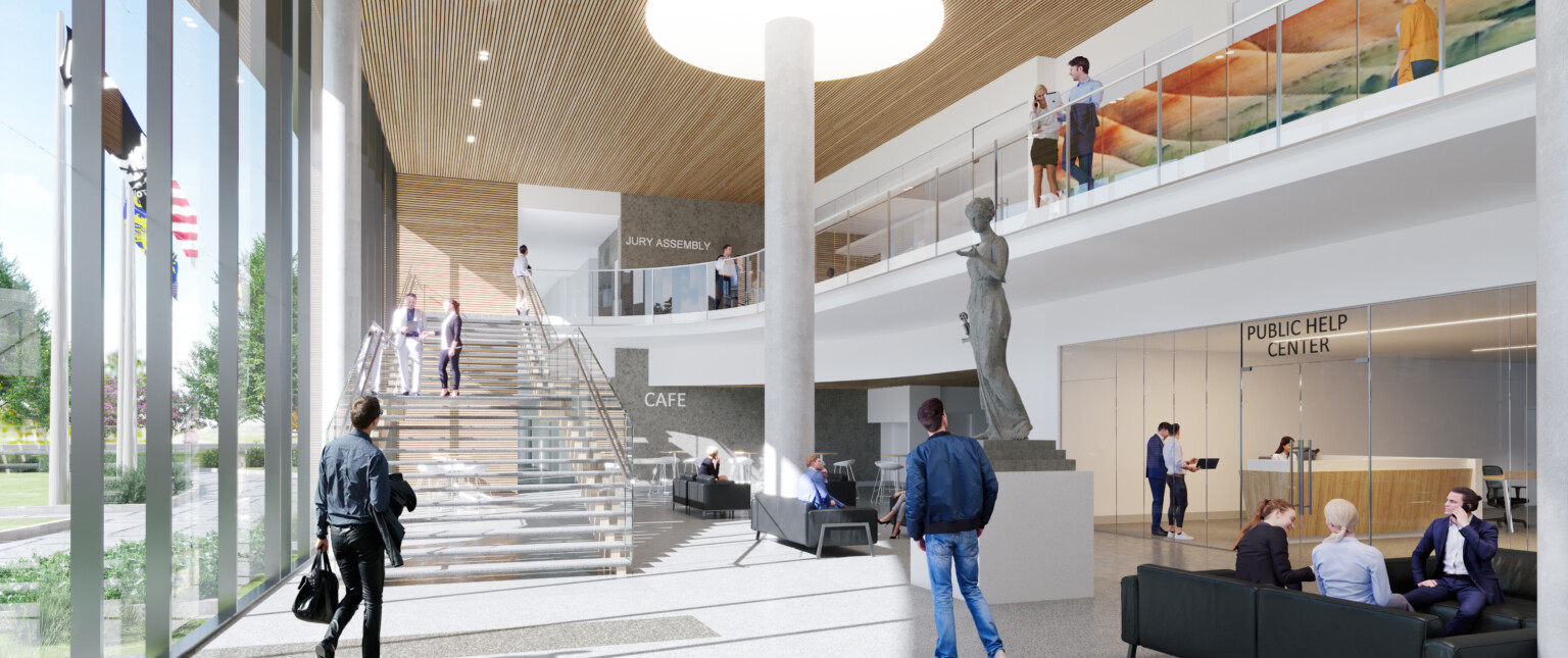 Two-story lobby space for public courthouse with a floating stair on the left leading to upper balcony. People walking around a statue of a woman and a structural pole in the center of the space, anchored by a light feature on the ceiling