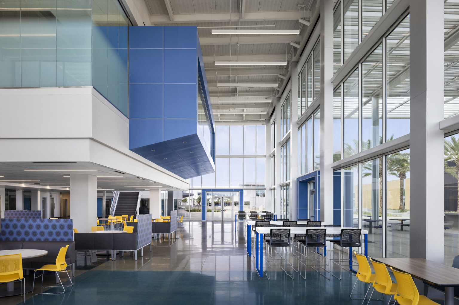 Common area in large double height hallway, closed off space above with blue accents