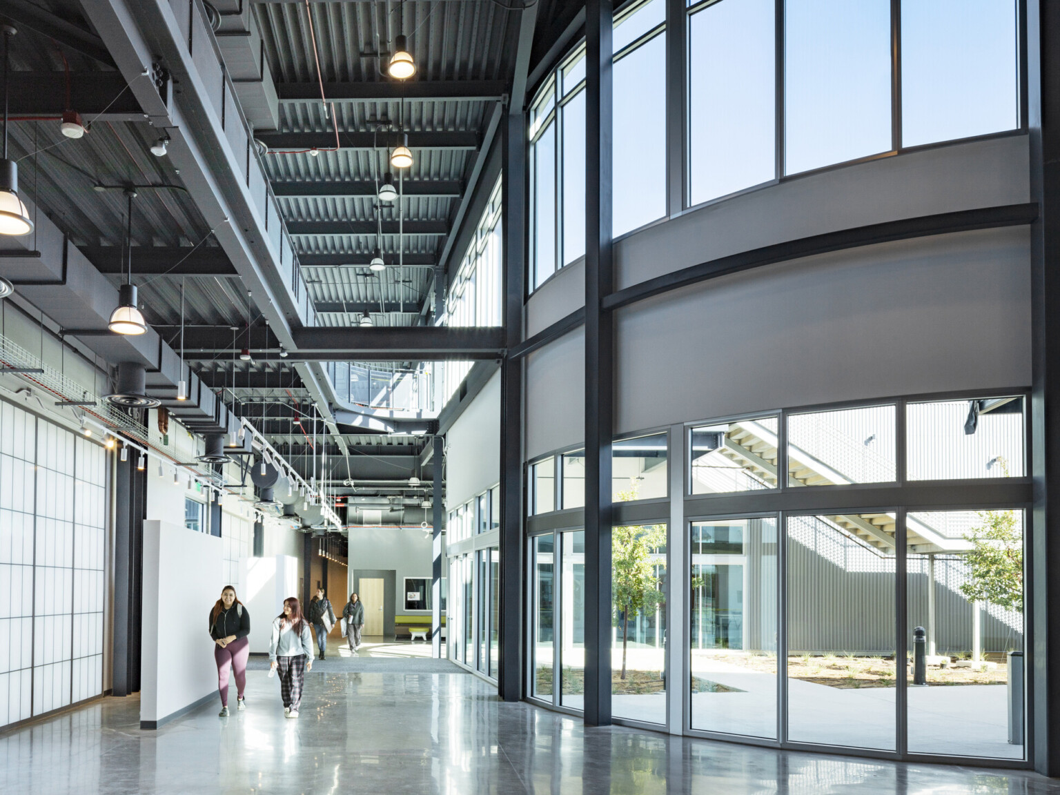 Glass and steel entryway from courtyard, floor-to-ceiling windows, high ceilings, polished concrete flooring