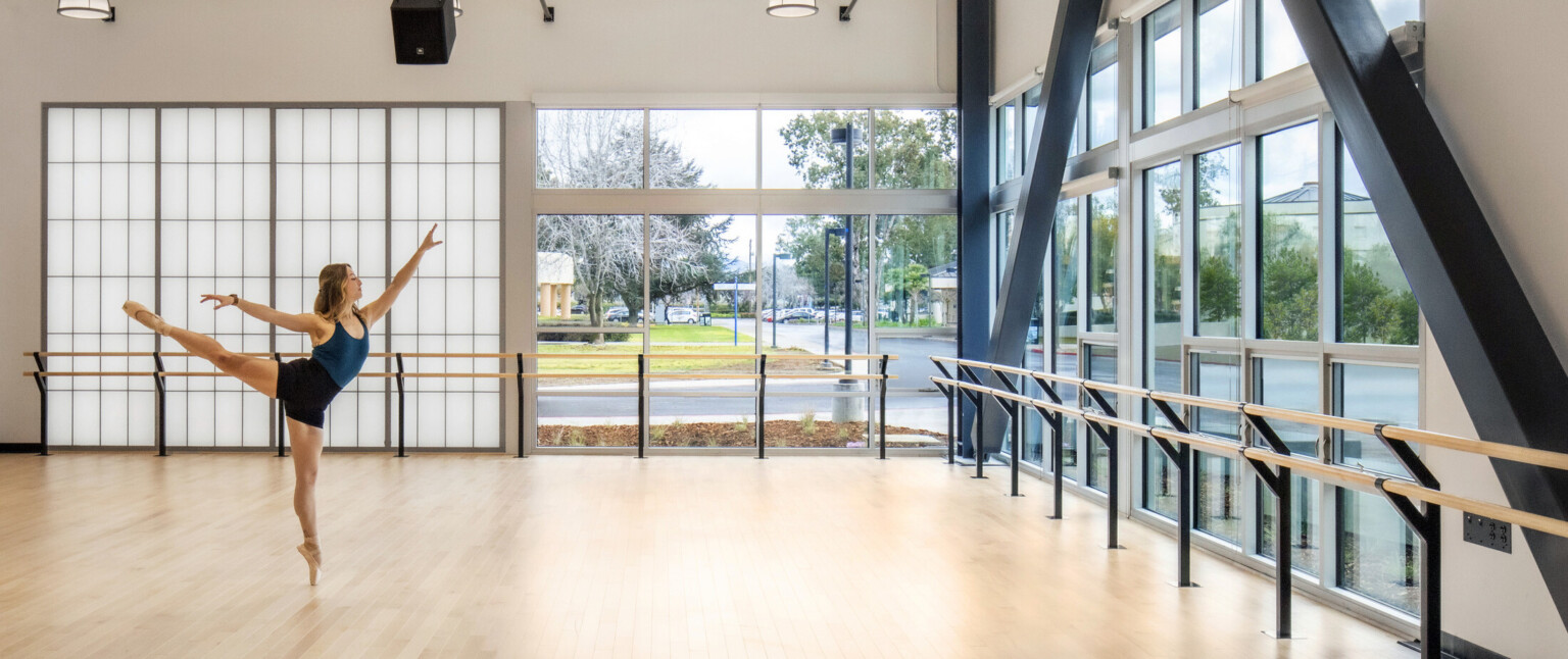 Natural daylight, sliding glass door brings the outdoors in to dance studio, warm natural hardwood flooring, metal beams, high-ceilings and a ballerina dancing