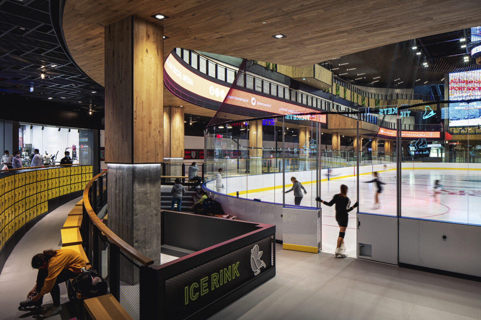 Indoor year-round ice rink in triple-height atrium, glass partitions, seating for watching and changing gear