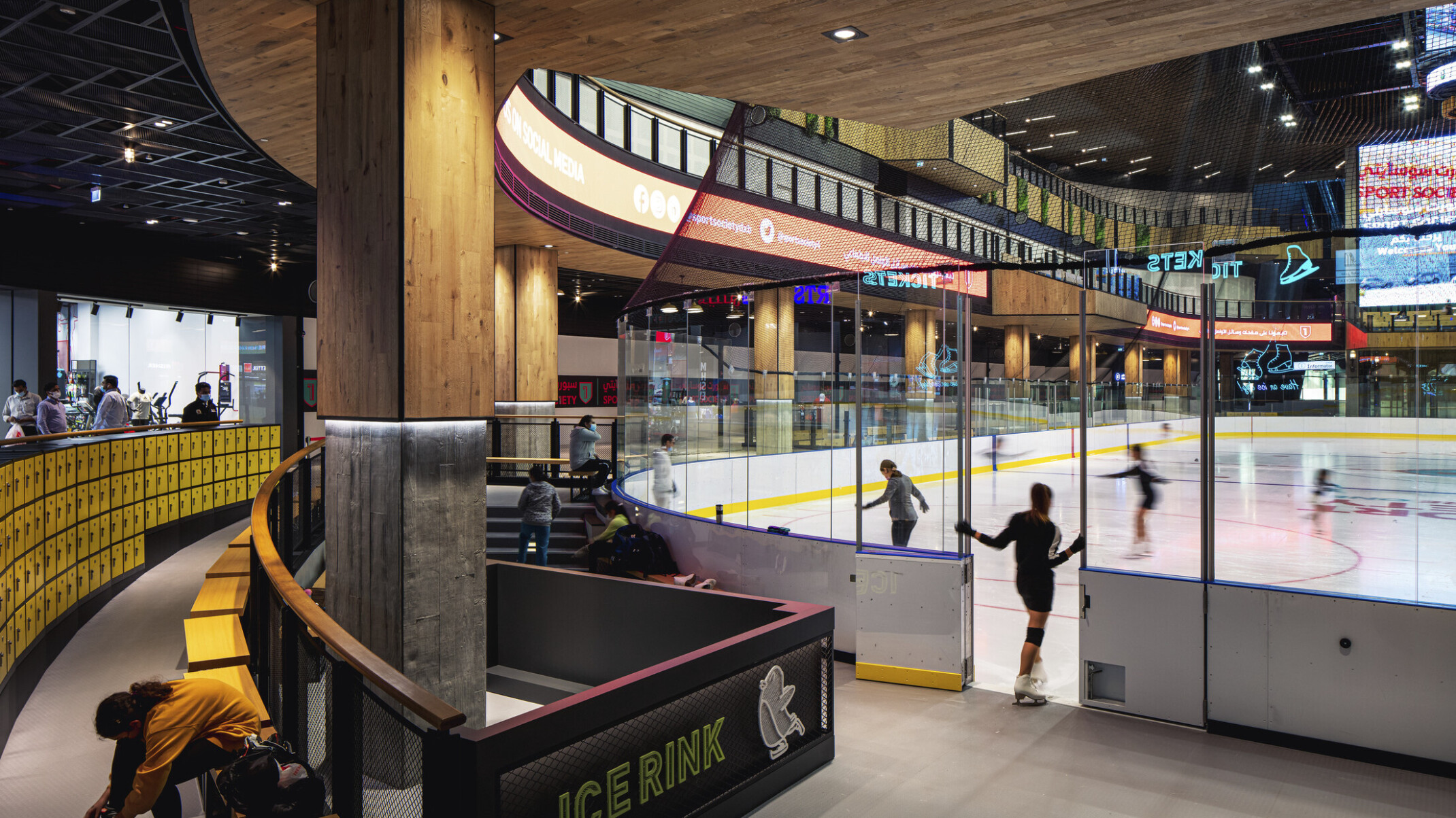 Indoor year-round ice rink in triple-height atrium, glass partitions, seating for watching and changing gear