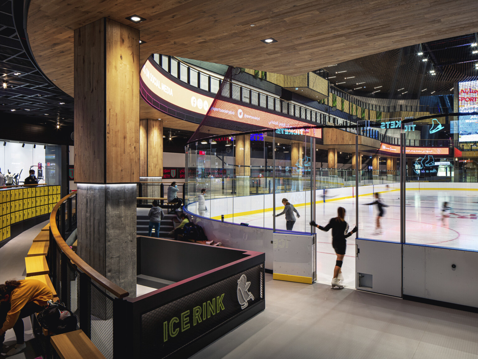 Indoor year-round ice rink in triple-height atrium, glass partitions, seating for watching and changing gear