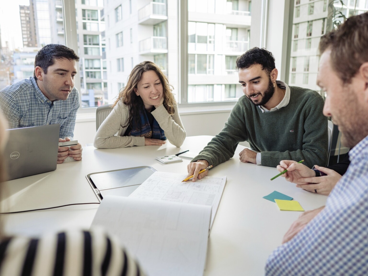 Group of Architects and Planners collaborating on a building project in a large, 22nd floor loft space with floor-to-ceiling windows on all sides, affording a 360 degree panoramic view of beautiful downtown Los Angeles