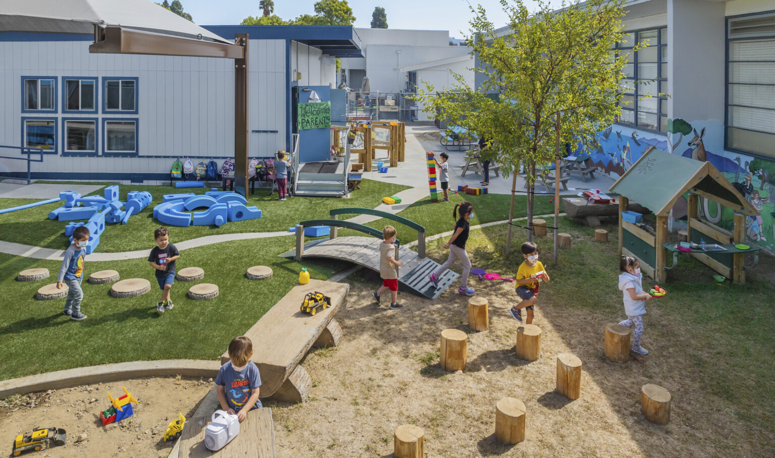 Children enjoying outdoor learning at Culver City Amazon Playground with custom sandbox, a bridge and surrounded by sunny skies