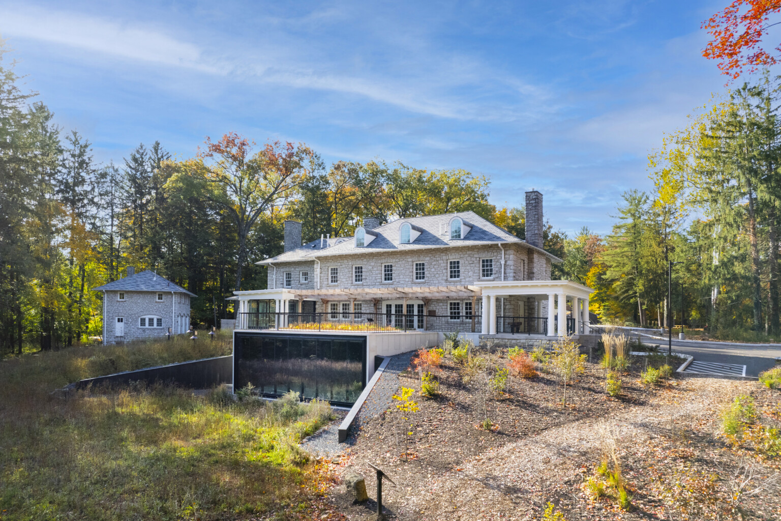 Stone façade mansion nestled in lush, tall trees, greenery, blue skies