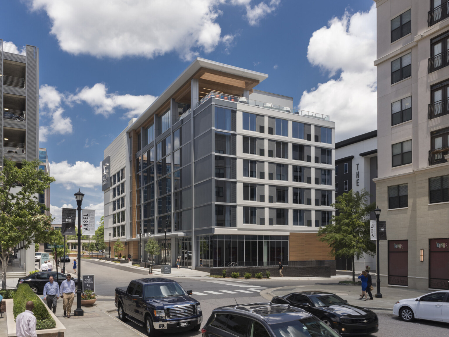 View up to corner of ac hotel in raleigh north carolina with a rooftop terrace, skylight in overhang, columns, large windows