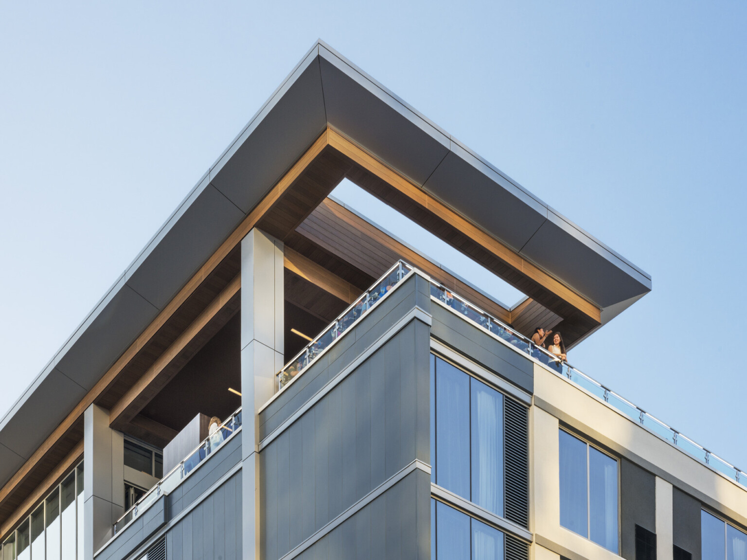 View up to corner of ac hotel in raleigh north carolina with a rooftop terrace, skylight in overhang, columns, large windows