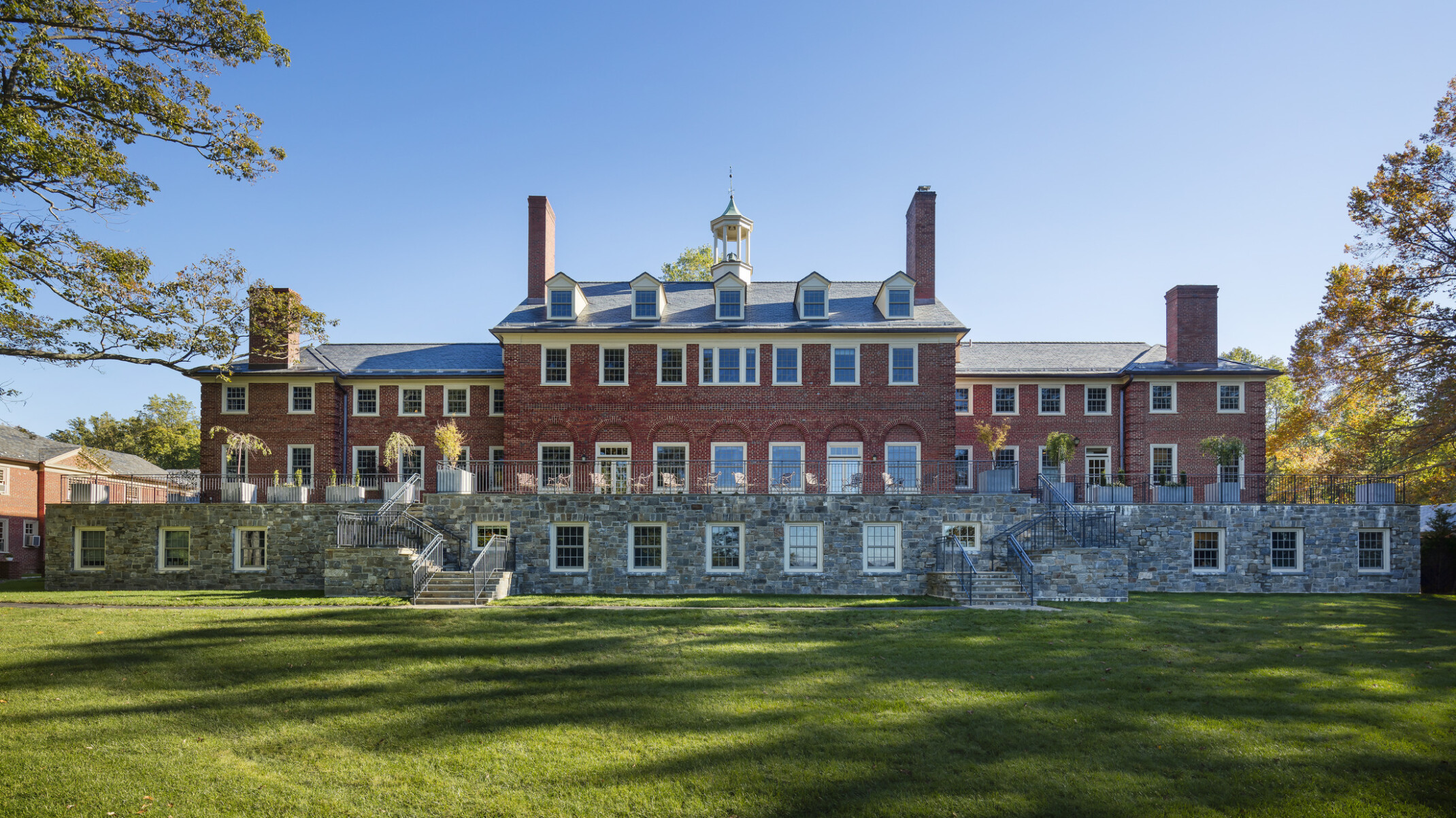 neo-Georgian historic three-story brick building, chimneys, blue skies, green grassy grounds, trees