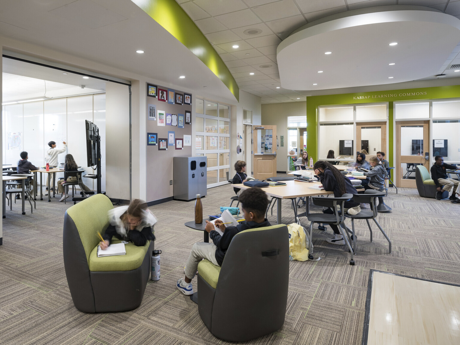 Whiteboard wall, left, in hall leading to Kassap Learning Commons, open room with flexible workspace and green accent wall