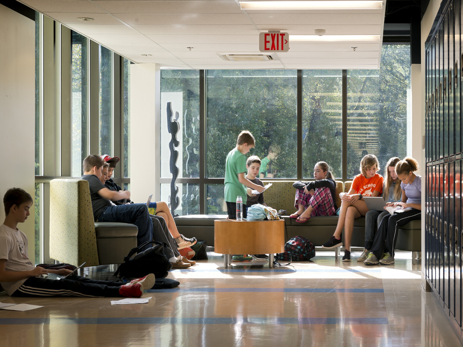 students gather in front of floor-to-ceiling windows to study, read or socialize, bench seating, coffee table