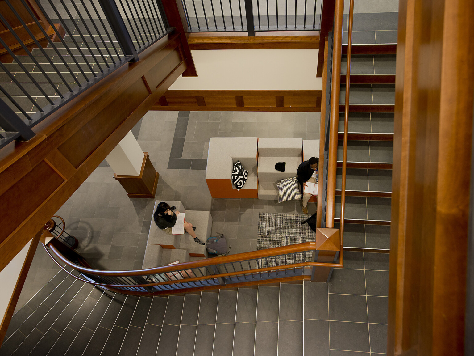 Aerial view from the top of a cherry wood stairwell, tile treads and risers, conversation seating on the bottom level