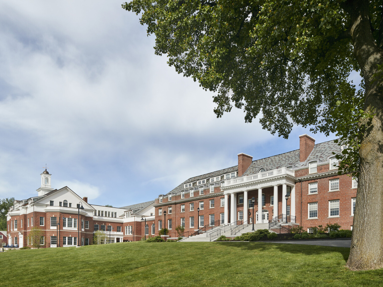 Exterior of Georgian Colonial Revival three story brick and white classical looking boarding school building with manicured lawn