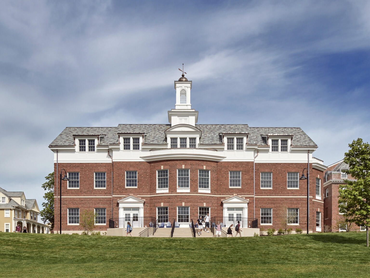 Exterior of Georgian Colonial Revival three story brick and white boarding school student center with white central bell tower