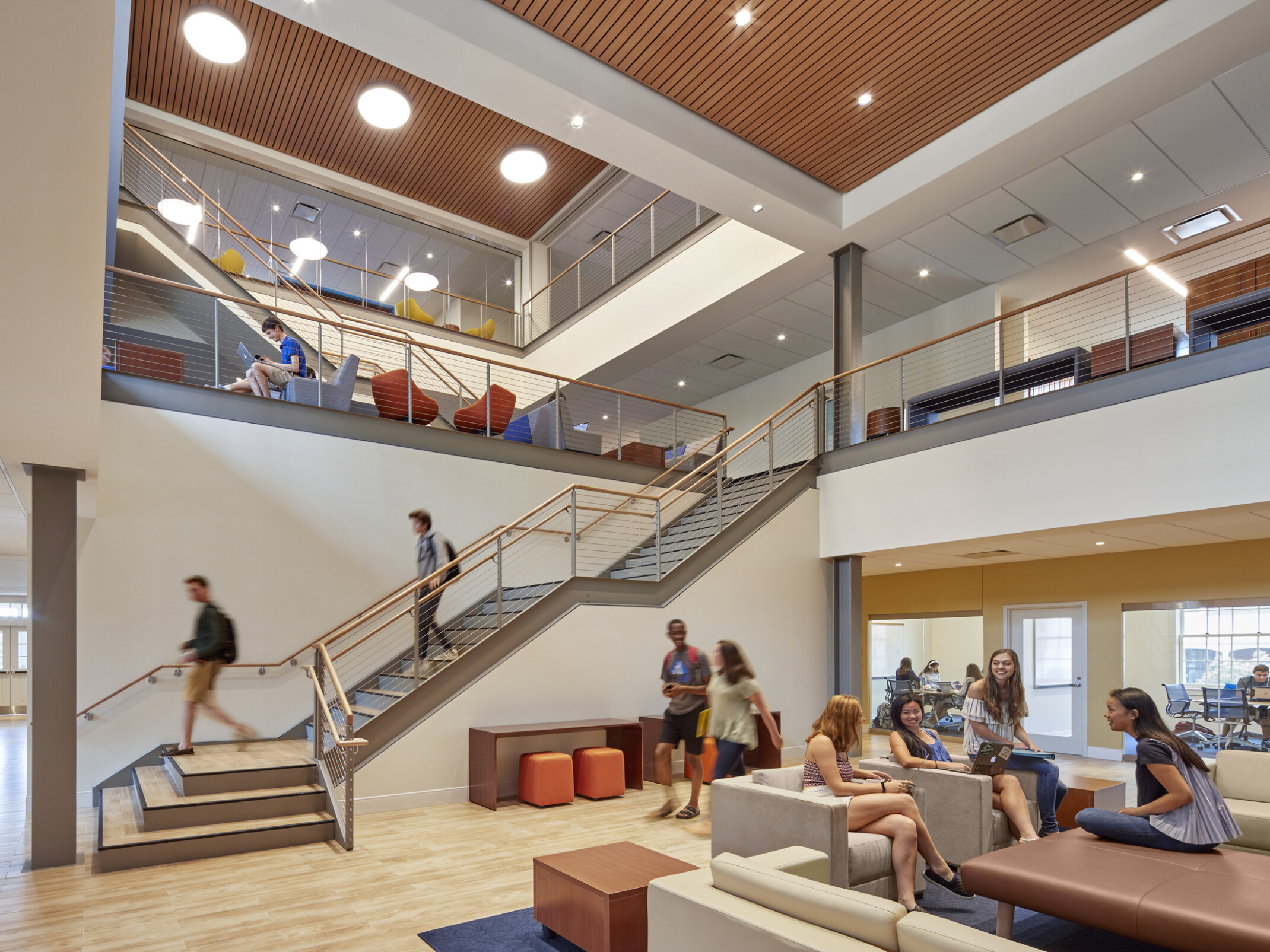Choate Rosemary Hall school's St. John Hall Student Center triple height atrium with wood panel ceiling accents over chairs