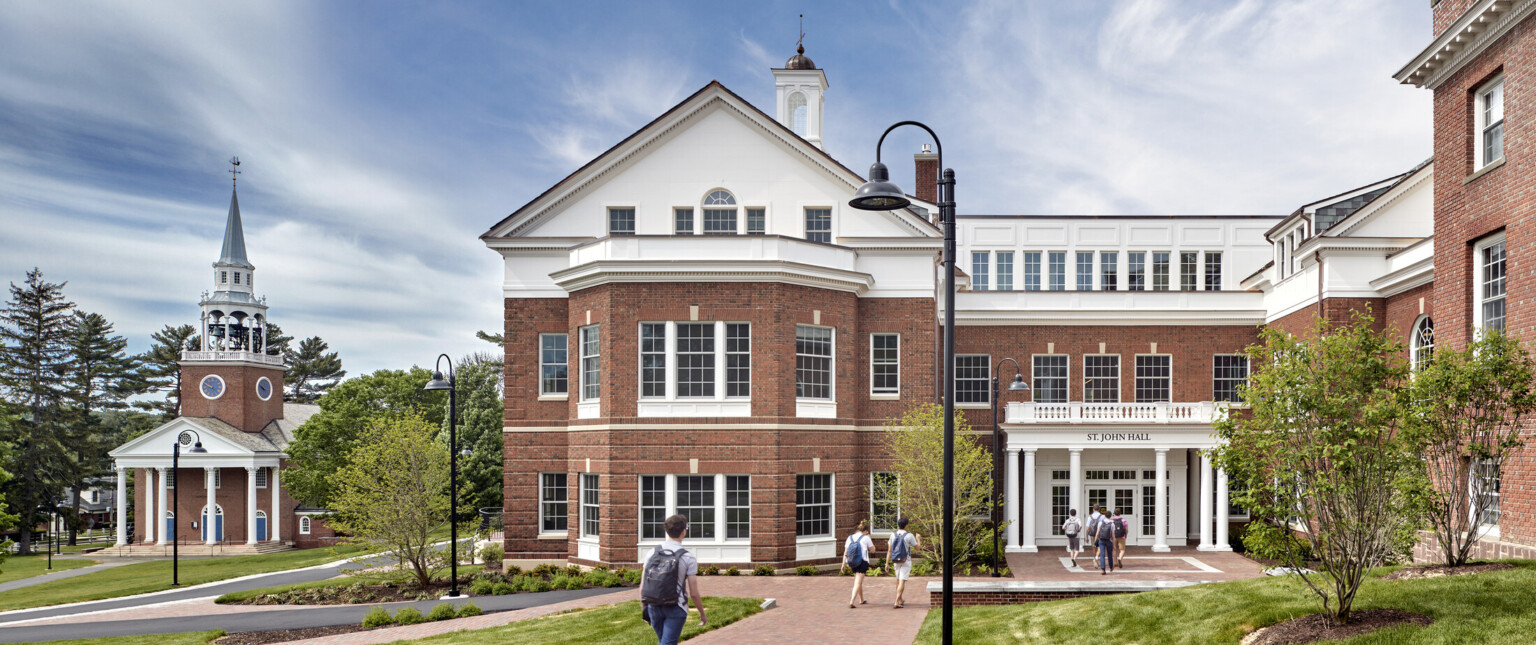 Exterior of Georgian Colonial Revival three story brick and white boarding school St John student center with stone walkway through grass