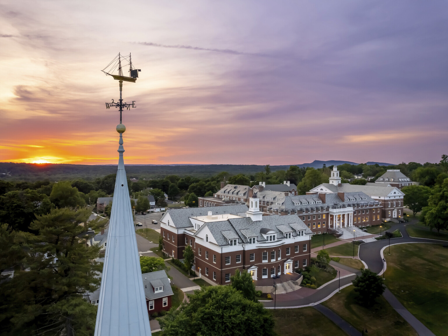 View of Choate Rosemary Hall's St. John Student Center and Hill House, seen from adjacent spire with ship weathervane at sunset