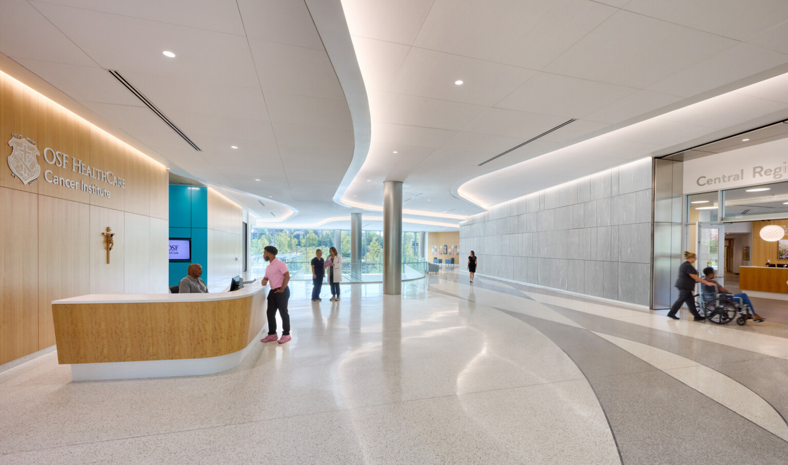Front desk area of the OSF Cancer Institute; people walking around the naturally lit space; doctors helping patients; clean white lines and design;