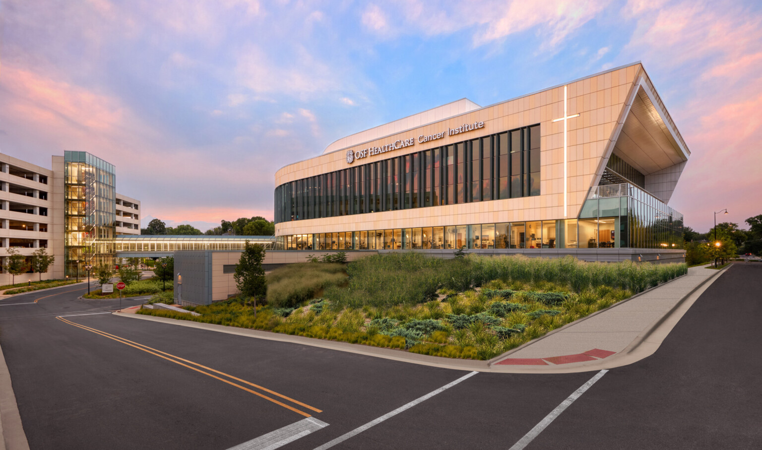 streetview of OSF Cancer Institute healthcare building during sunset; large modern windows and curved design to the building