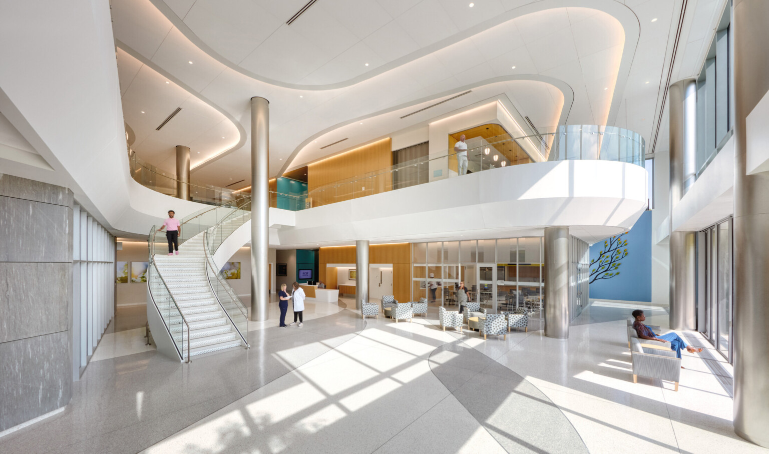 Inside image of OSF Cancer Institute and Proton Therapy; Modern, sleek and mostly white design with balcony and staircase down to the waiting area