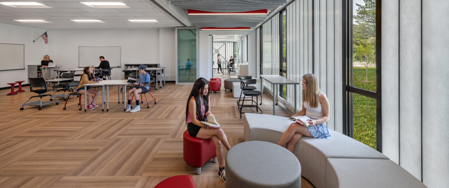 Large classroom with wooden floors, white furniture, black framed windows and lots of natural light