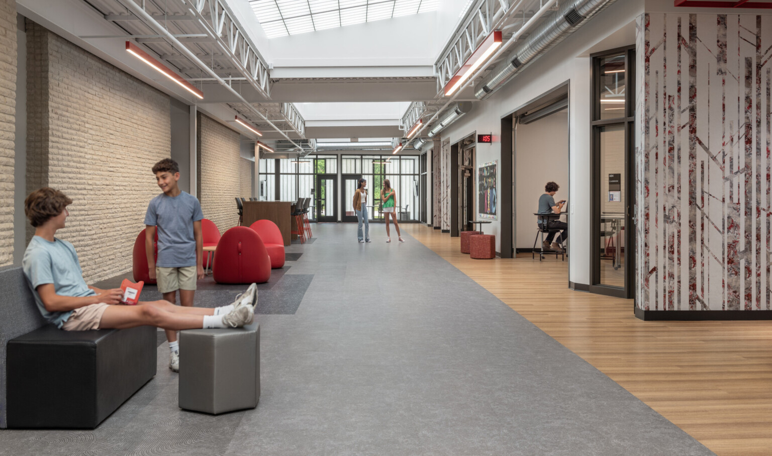 Two male students talking in a school hallway with grey floors and natural lighting