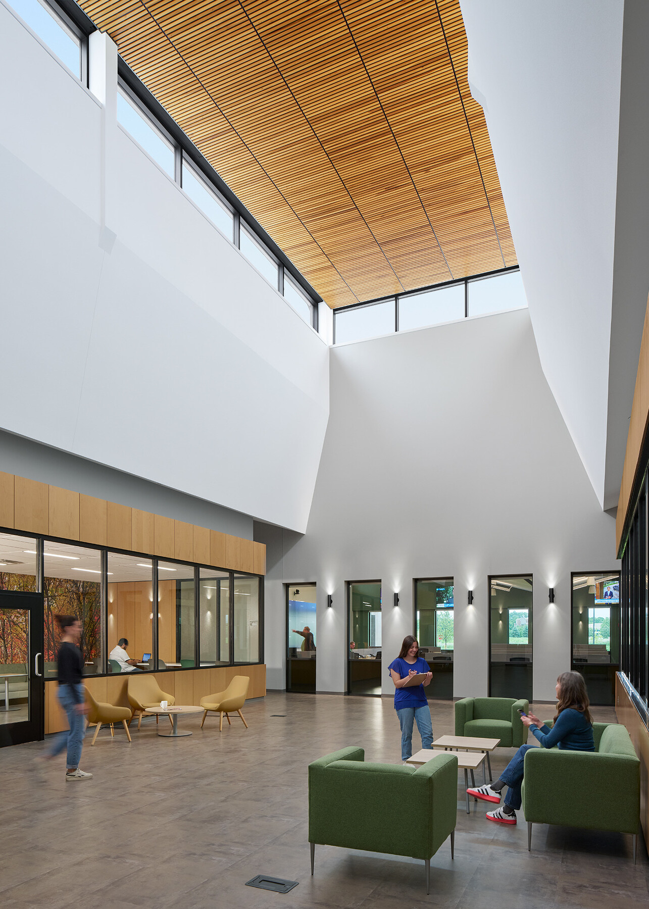 Palo Alto Public Safety Building & Emergency Operations Center; Detectives in suits and uniformed police officers sit in conversation at café tables and soft seating in a double-height atrium