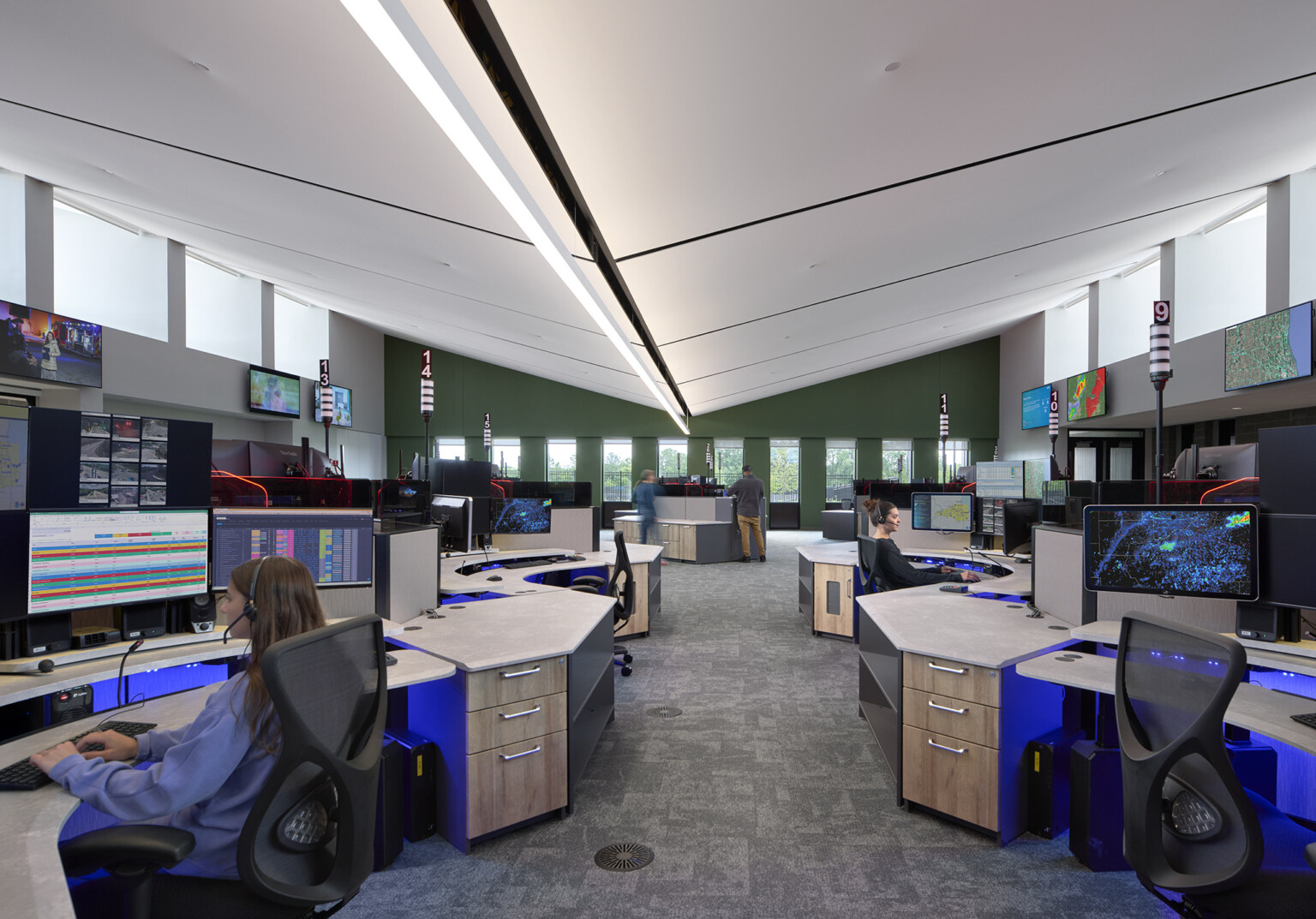 lake county regional emergency operations center with modern bull pen desking room with people working at multiple desktops; TV screens along the double height wall