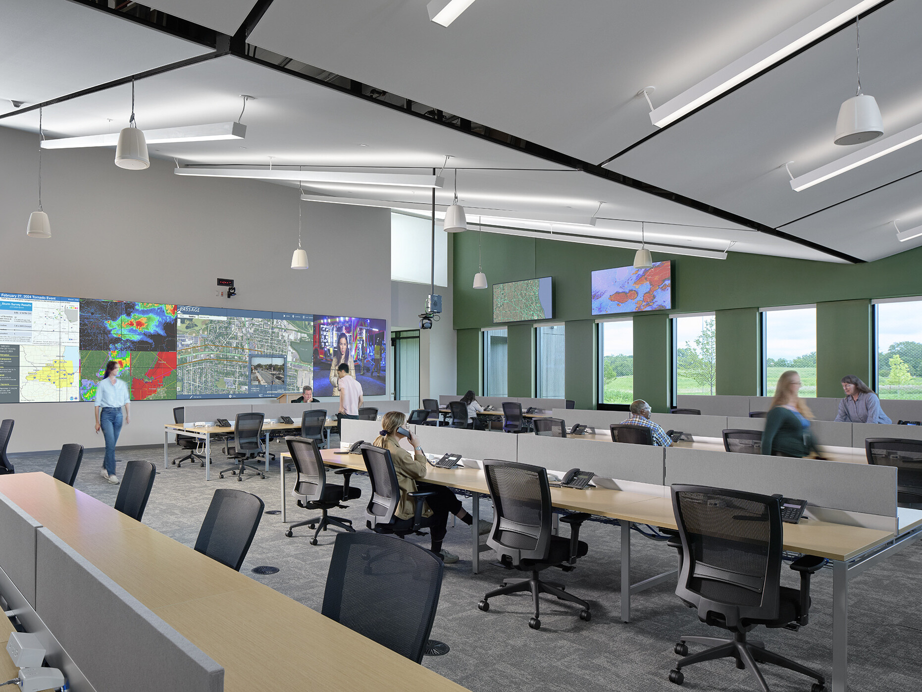 emergency operations center with large screens and TVs facing benched desks with phones and office chairs