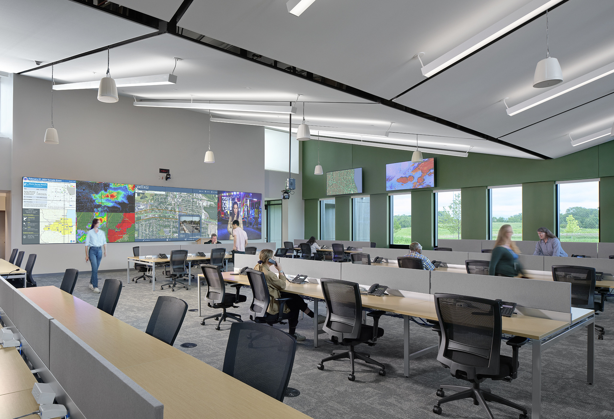 emergency operations center with large screens and TVs facing benched desks with phones and office chairs