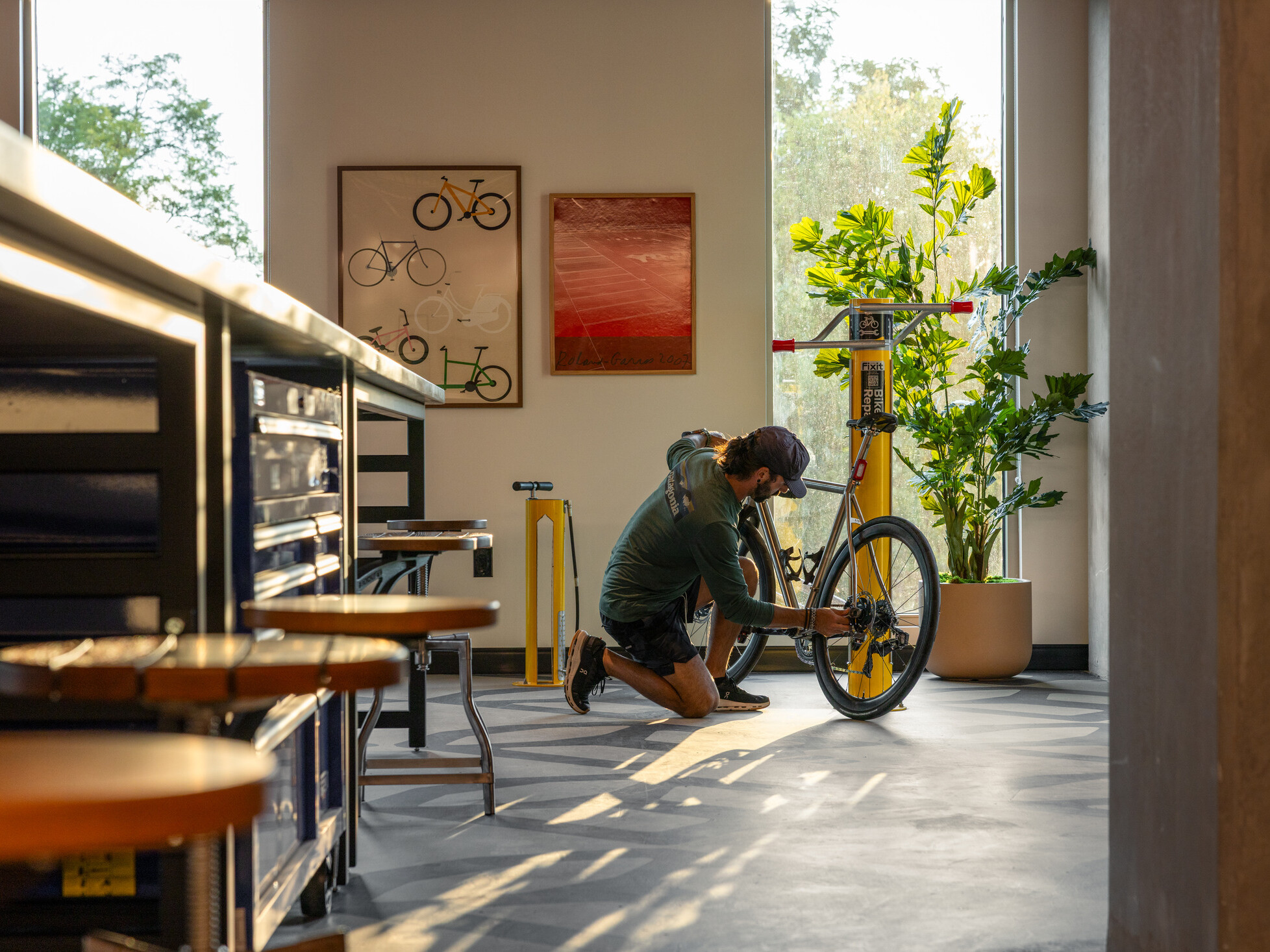 modern apartment bike room; floor level POV with a man adjusting his bike at the end of the hallway