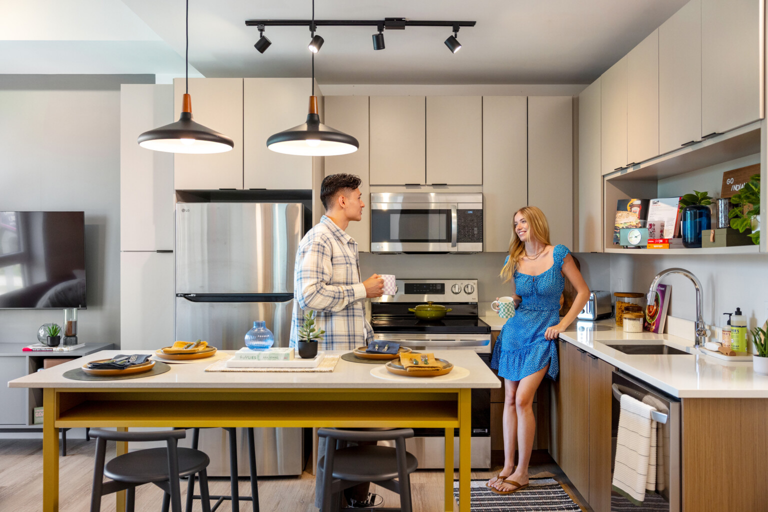 Hub Bloomington off campus student housing; Students using an in-unit kitchen with light gray cabinetry and wood finishes.