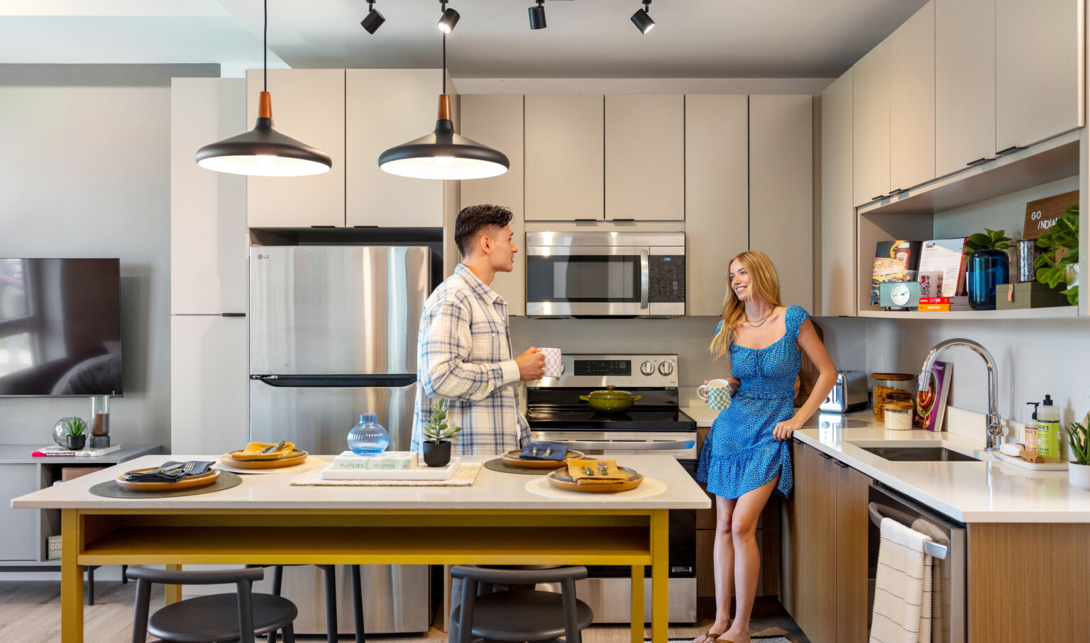 Hub Bloomington off campus student housing; Students using an in-unit kitchen with light gray cabinetry and wood finishes.