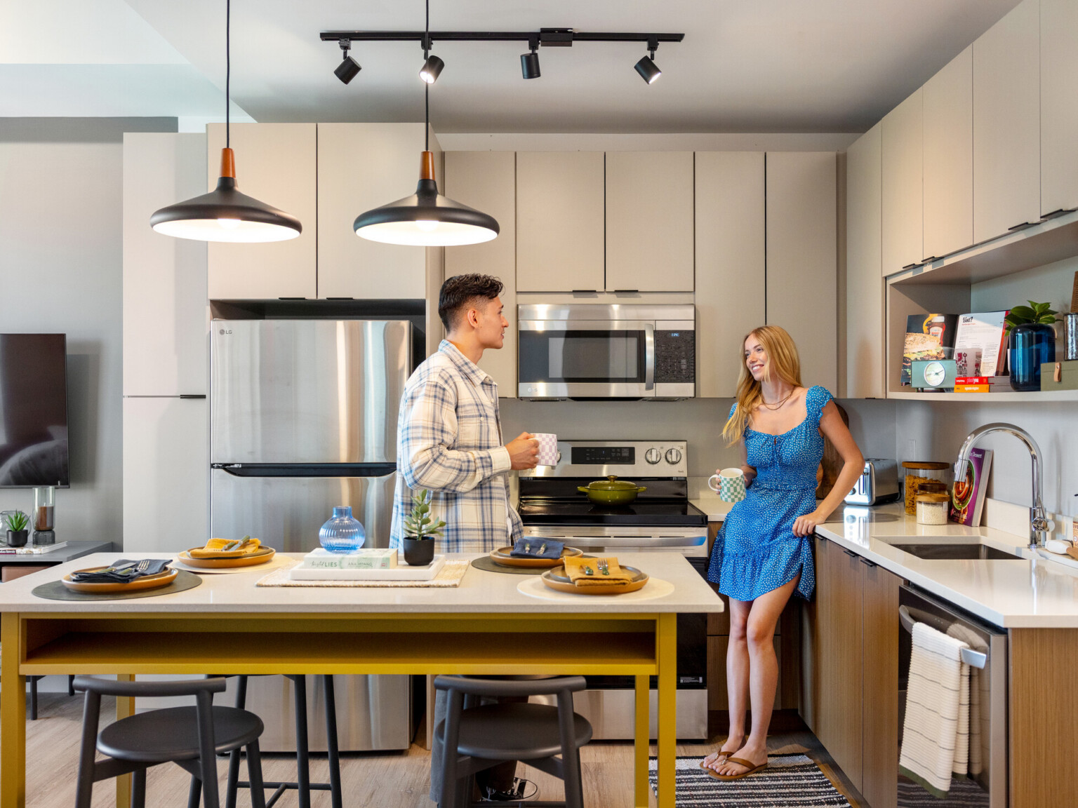 Hub Bloomington off campus student housing; Students using an in-unit kitchen with light gray cabinetry and wood finishes.