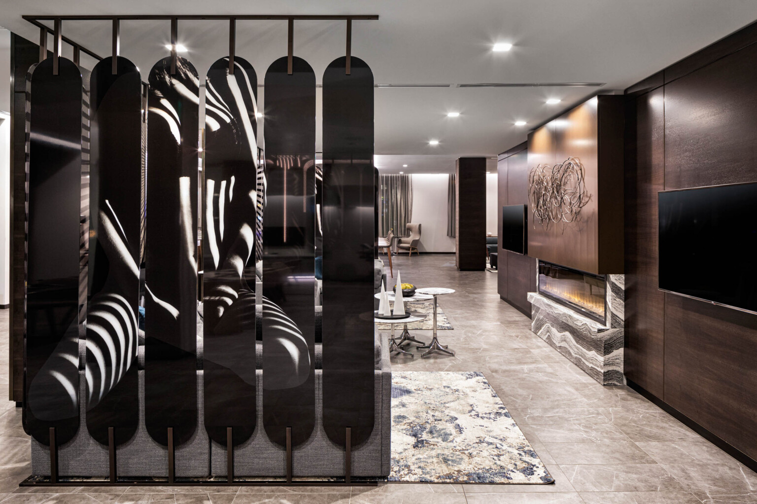 AC Hotels by Marriott follows the Marriott brand architecture and features a sculptural divider in a monochromatic lobby with wood panel wall and fireplace