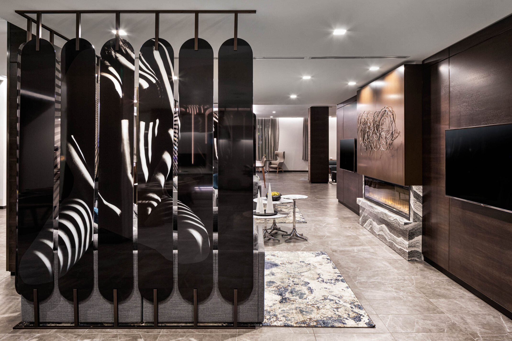 AC Hotels by Marriott features a sculptural divider in a monochromatic lobby with wood panel wall and fireplace