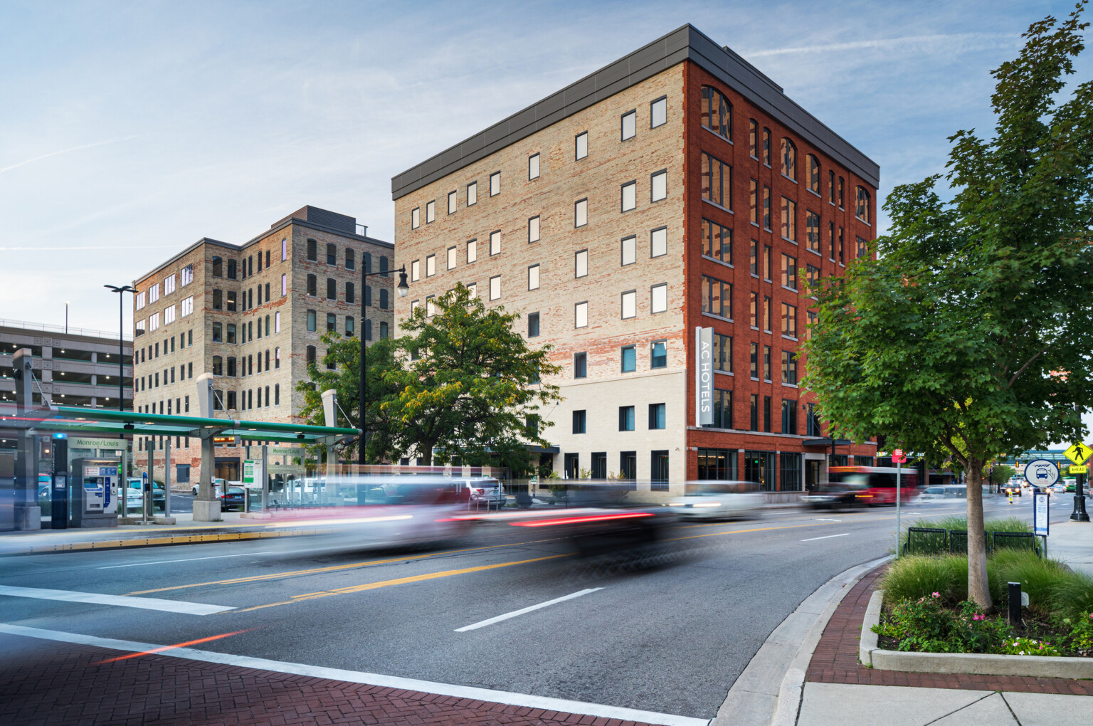 A pair of brick façade buildings, built in 1890, once a warehouse is now AC Hotel Grand Rapids Downtown, a hotel in a bustling downtown