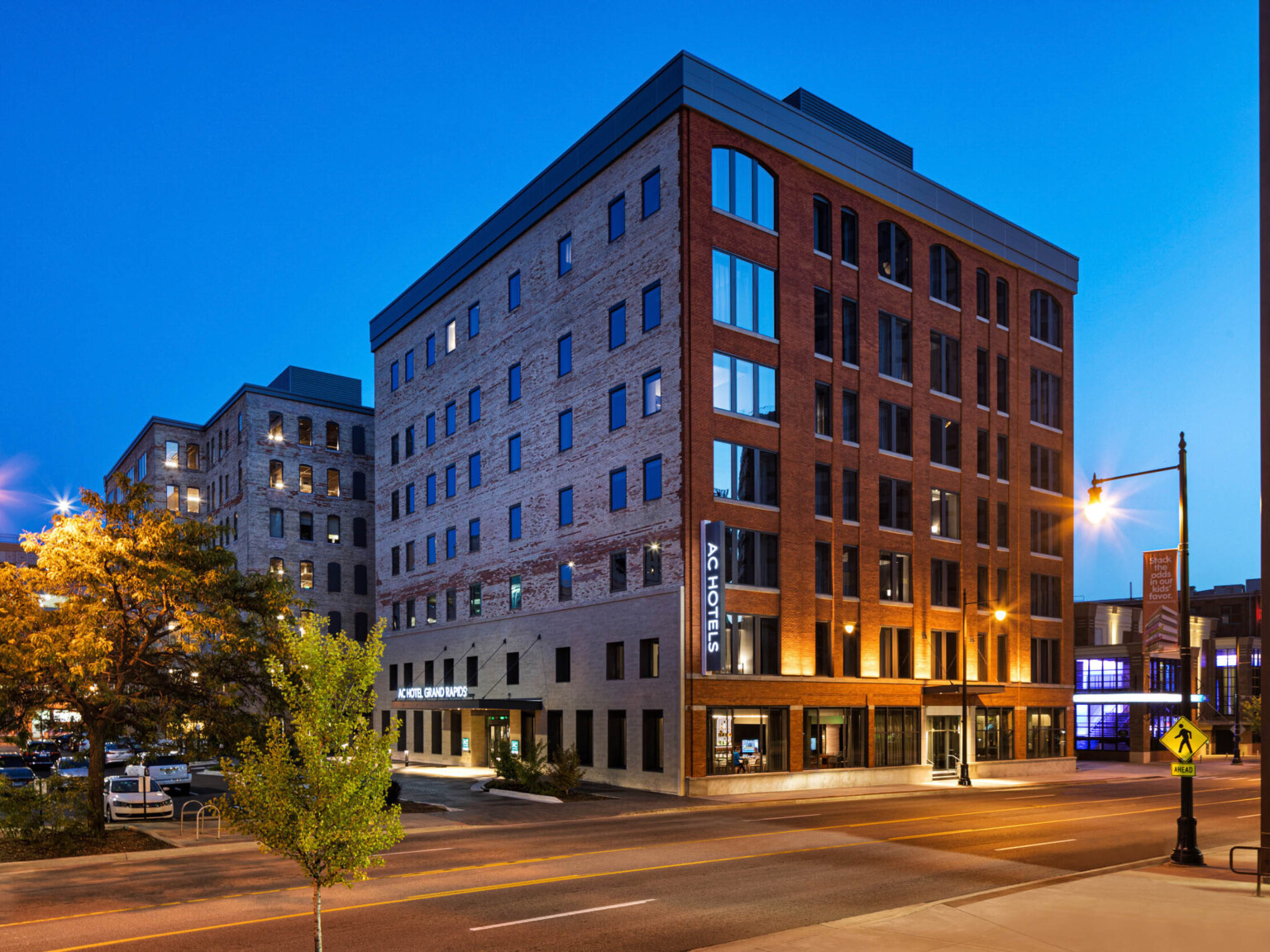 View of building corner from across the street. Main entrance on the left with stone first two stories, exposed brick on rest following Marriott brand architecture