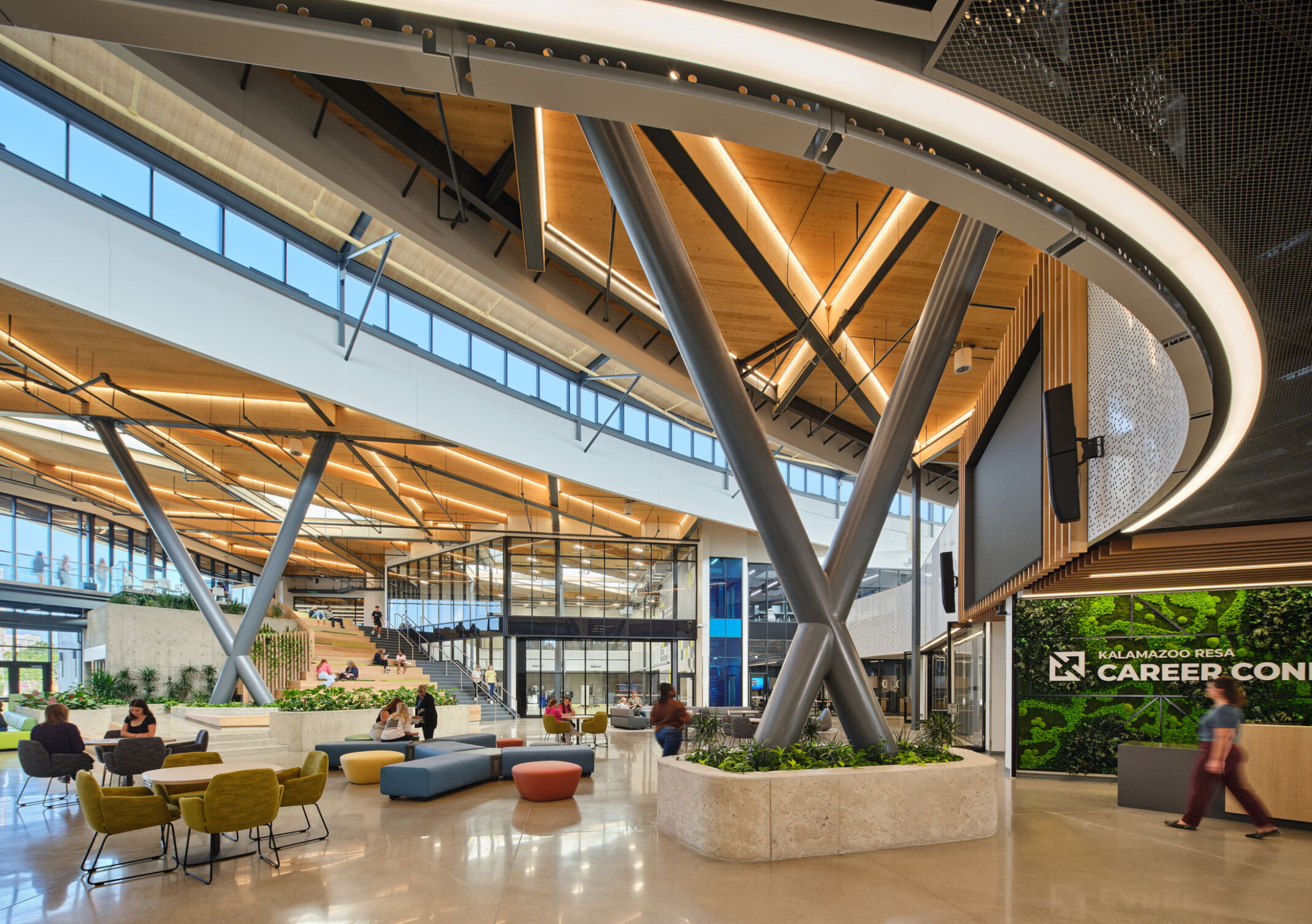 Kalamazoo RESA career technical education central open area featuring exposed wood structure, natural materials, and biophilic design elements; modular community seating
