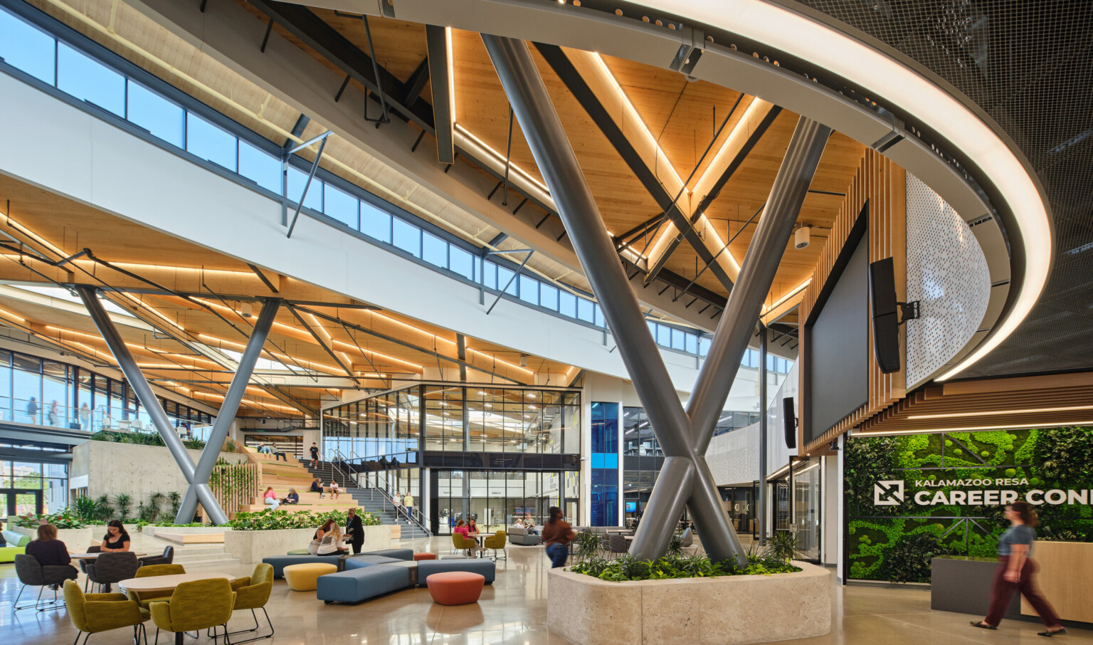 Kalamazoo RESA career technical education central open area featuring exposed wood structure, natural materials, and biophilic design elements; modular community seating