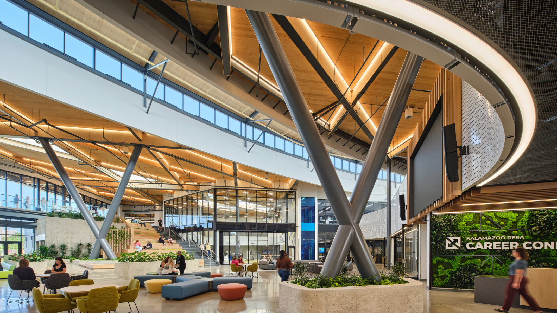 Kalamazoo RESA career technical education central open area featuring exposed wood structure, natural materials, and biophilic design elements; modular community seating